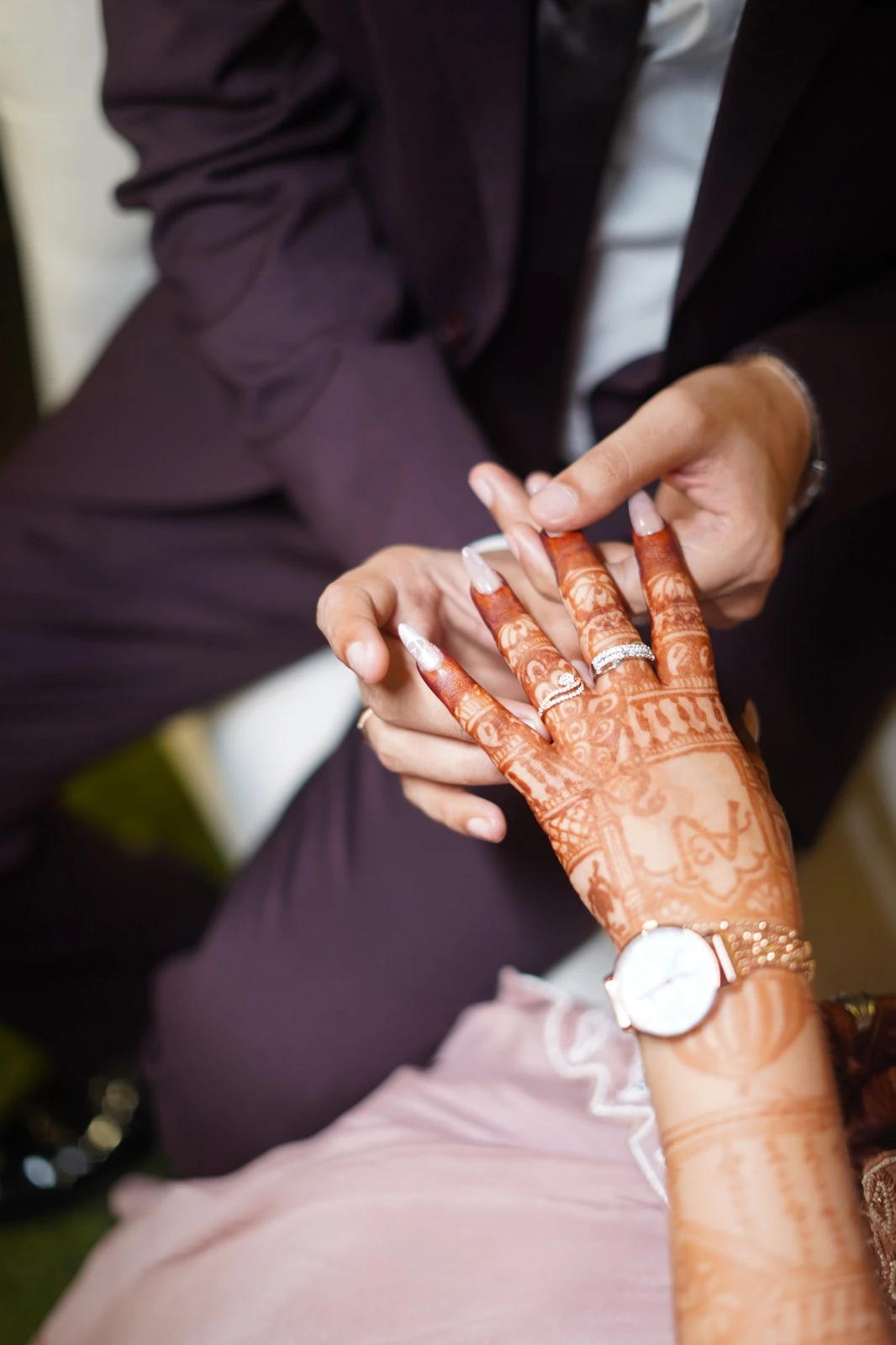 Their hands together, with mehendi and engagement rings